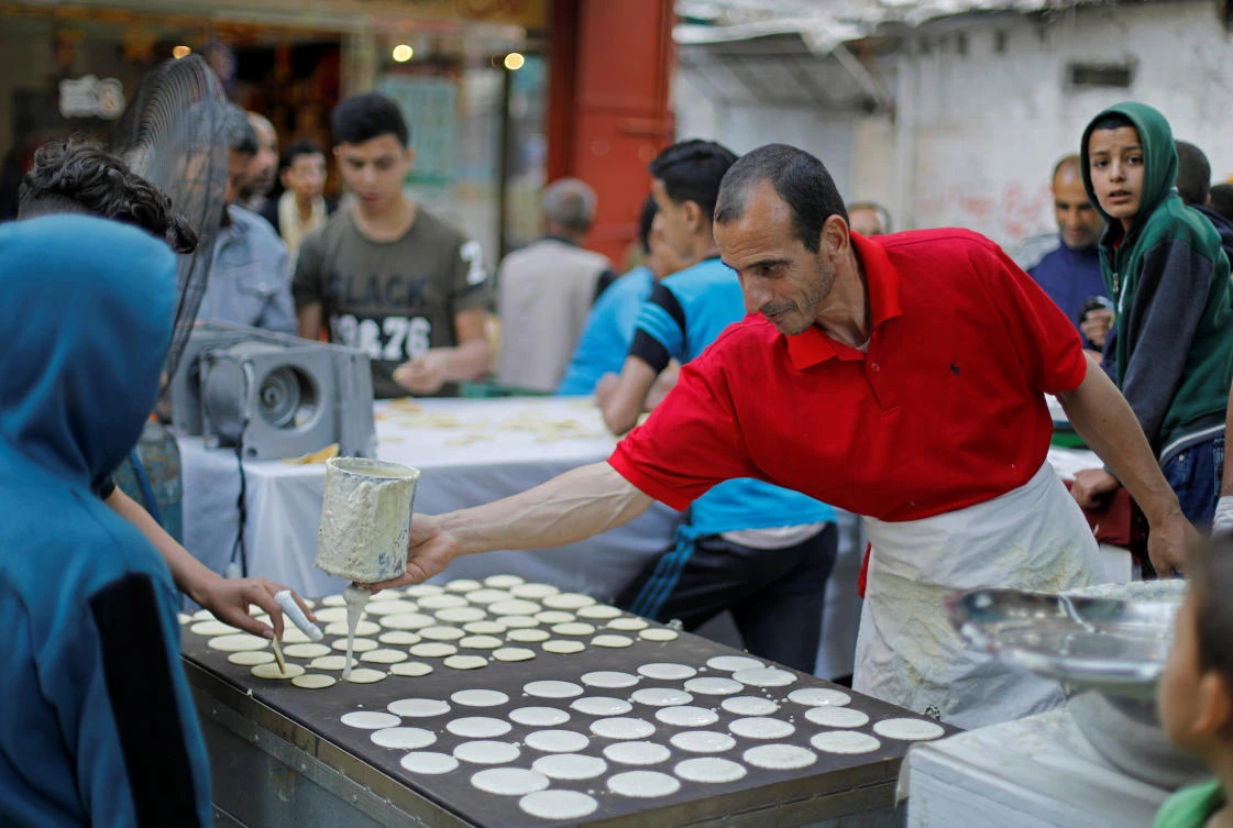 A Palestinian vendor makes Ramadan traditional sweets during Ramadan, amid concerns about the spread of the coronavirus disease. (REUTERS)