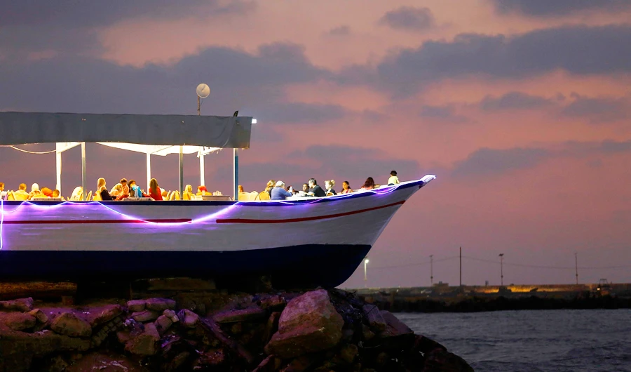 A picture taken on August 2, 2017 shows Palestinians dining at dusk at a restaurant made from a beached boat, by the coast in Gaza City. (AFP)