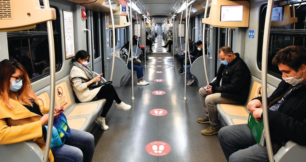People ride a subway with social distancing signs on the floor. Reuters Women practicing social distancing in a subway train in Milan. (AP)