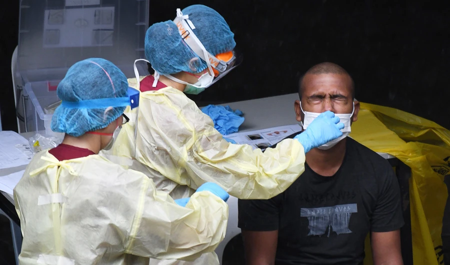 A Singaporean health care worker dressed in personal protective equipment collects a nasal swab sample from a migrant worker for testing for the coronavirus. (AFP)