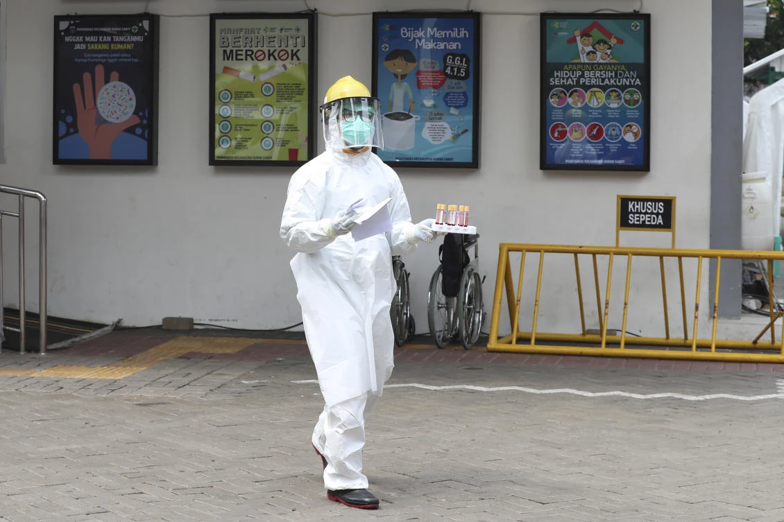 A health worker carries blood samples during a rapid test for the new coronavirus at a hospital in Jakarta, Indonesia, Tuesday, April 28, 2020. (AP)