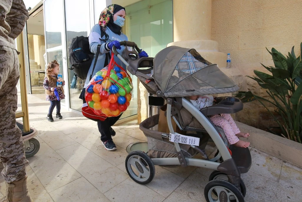 A mask-clad woman with her children leave a Dead Sea resort where they have been quarantined on March 30, 2020. (AFP)