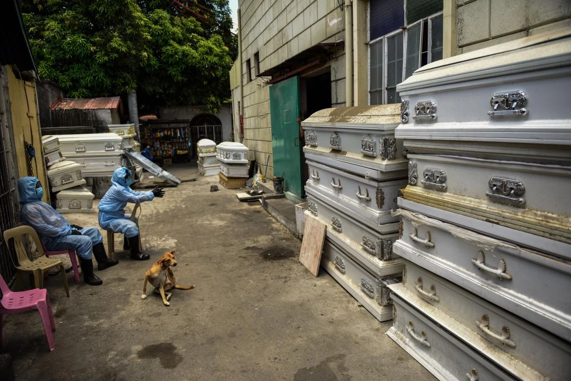 Workers in protective suits wait outside a crematorium facility as the cremation process takes some two hours in Manila on April 29, 2020. (AFP)