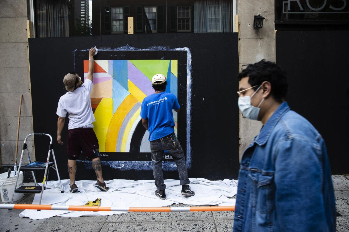 Workers affix a poster to a shuttered business in Philadelphia, Monday, May 4, 2020. The Center City District and Mural Arts Philadelphia posted the original works on multiple locations in an effort to enhance the neighborhood awash with business shuttered to help curb the spread of coronavirus. (AP Photo/Matt Rourke)