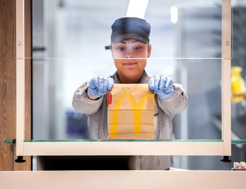A McDonalds’ employee holds up a food package at a test location in a restaurant at The GelreDome Arnhem, The Netherlands on May 1, 2020, as part of measures to attempt to stop the spread of COVID-19 (novel coronavirus). (AFP)