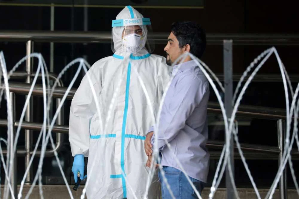 A police officer wearing protective suit picks up an illegal immigrant from an apartment in Kuala Lumpur, Malaysia, on May 1, 2020 under a lockdown order to control the spread of the COVID-19 virus. (REUTERS/Lim Huey Teng)