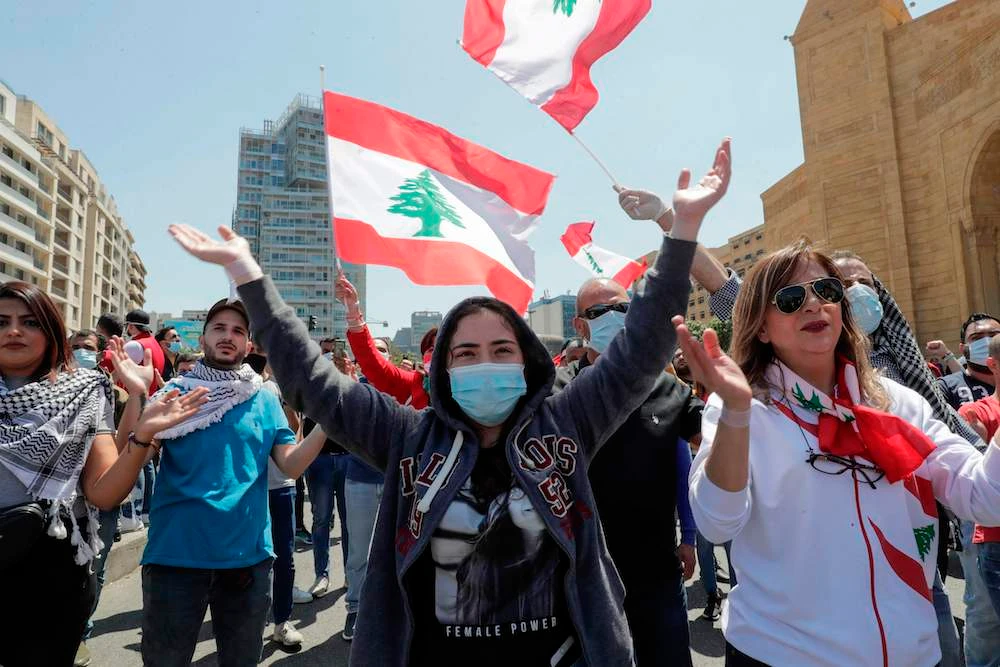 Lebanese anti-government protesters, some wearing protective masks amid the COVID-19 pandemic, gesture during a demonstration against the growing economic hardship in downtown Beirut on May 1, 2020. (AFP)