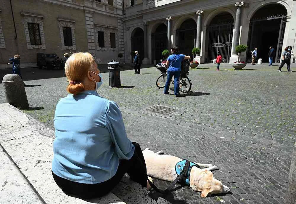 People sit in Rome's Santa Maria in Trastevere square on Sunday. Italians will be free to stroll and visit relatives for the first time in nine weeks on Monday. (AFP)