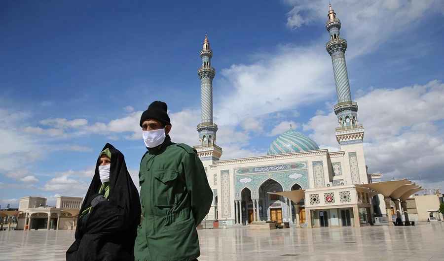 A couple wearing protective face masks, following the outbreak of coronavirus disease (COVID-19), walks on the street in Qom, Iran March 24, 2020. WANA (West Asia News Agency) via REUTERS