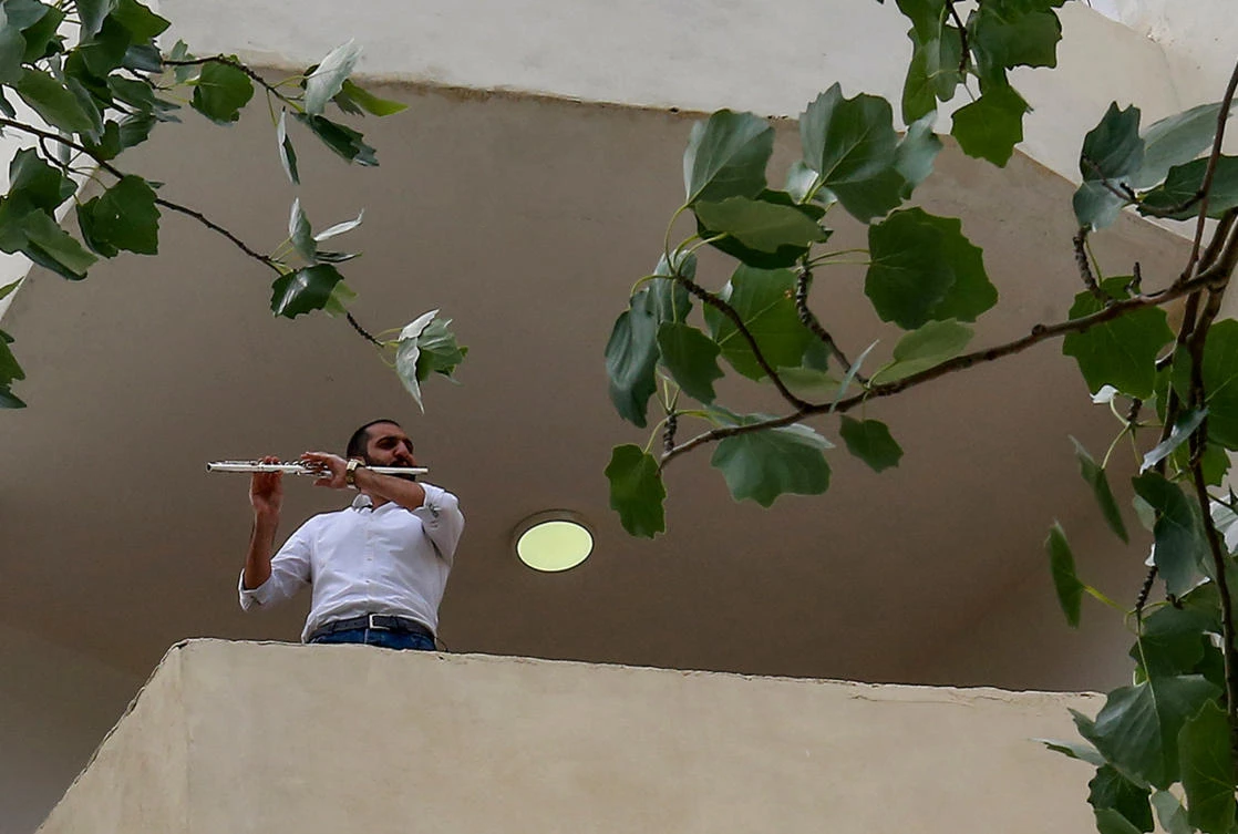 Ebaa Akroush, a 24-year-old Jordanian music graduate from the University of Jordan and first-prize winner of a culture ministry talent contest, plays the flute on his balcony in Fuheis town, around 20 kilometres northwest of the capital Amman, on April 27, 2020. (AFP)