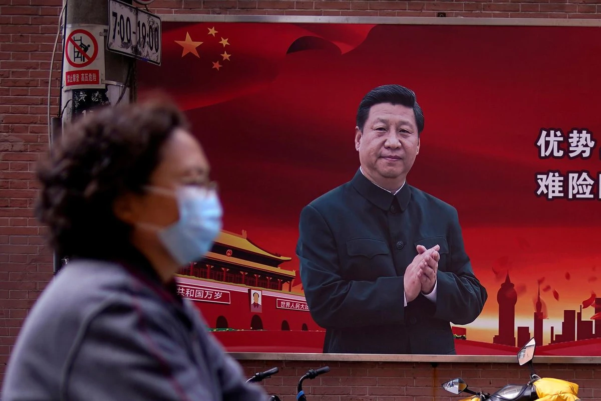 In this file photo, a woman wearing a protective mask is seen past a portrait of Chinese President Xi Jinping on a street in Shanghai, China, March 12, 2020. (REUTERS/File)
