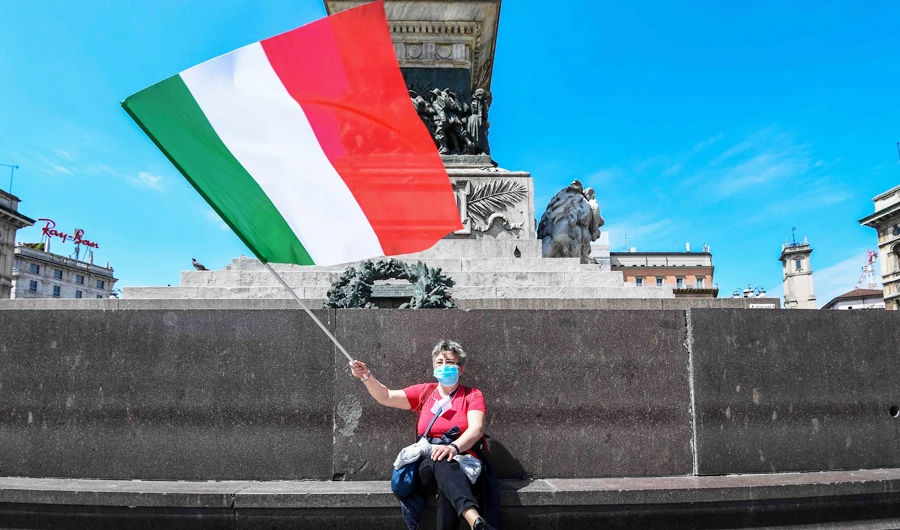 A woman waves the Italian flag in Milan as Italy starts to ease its lockdown caused by the coronavirus. Italy has officially attributed 28,884 deaths to the virus. (AFP)