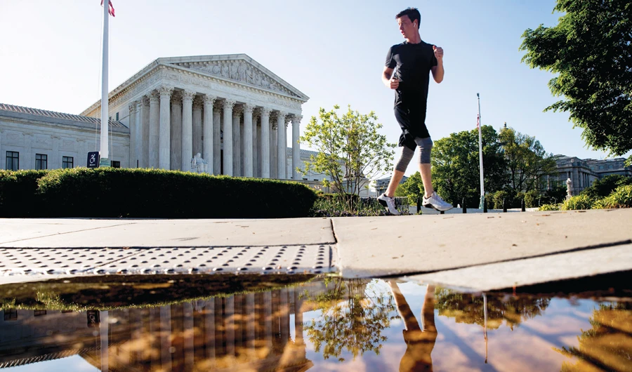 A man runs past the Supreme Court where the justices held arguments by telephone for the first time ever on Monday. (AP)