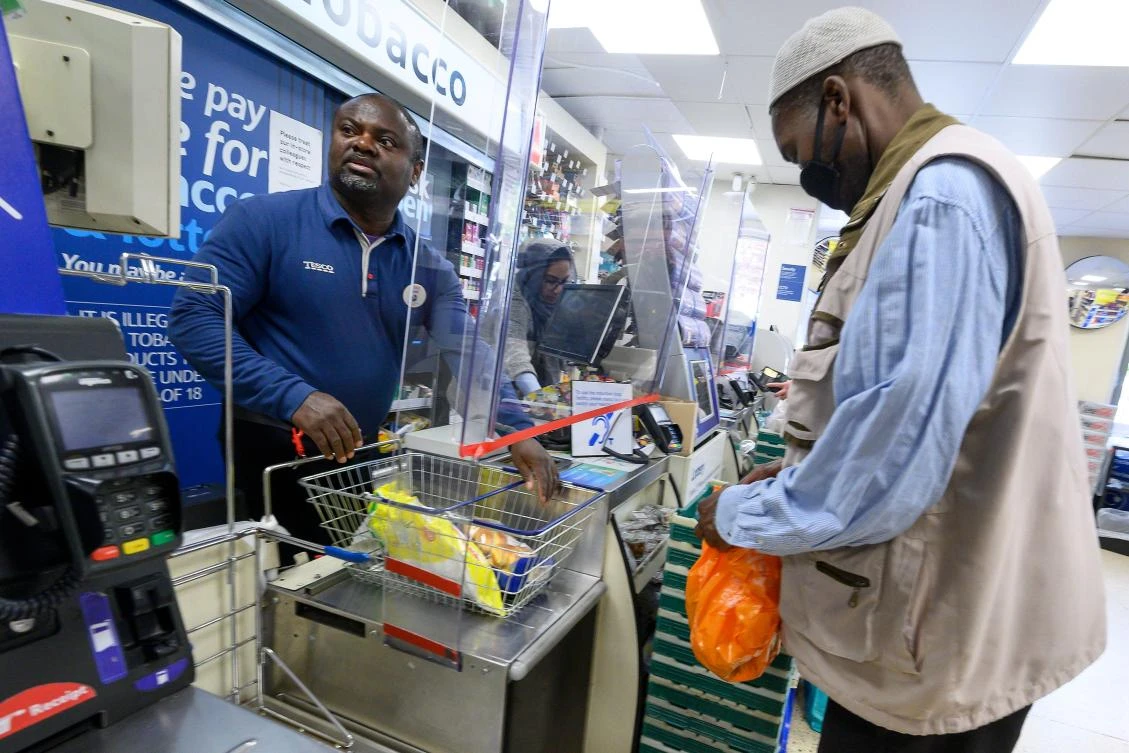 A cashier at a Tesco supermarket works behind a protective perspex barrier in Croydon, south London. (AFP)