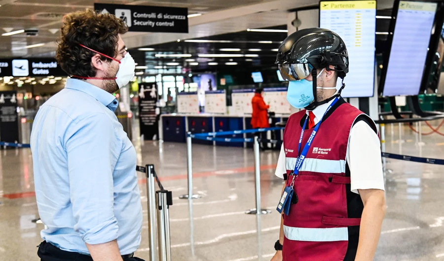 A Fiumicino airport employee wearing a "Smart-Helmet" portable thermoscanner to screen passengers and staff for COVID-19 (R), scans a fellow airport staff at boarding gates on May 5, 2020 at Rome's Fiumicino airport during the country's lockdown aimed at curbing the spread of the COVID-19 infection, caused by the novel coronavirus. (AFP)