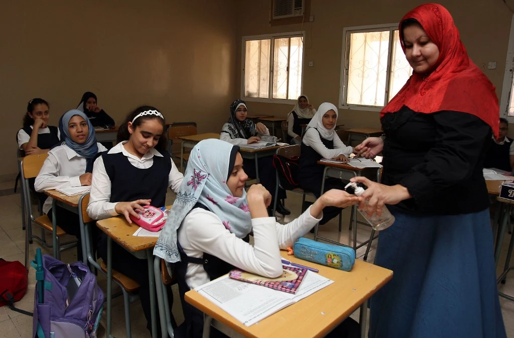 A teacher puts disinfectant hand gel on a student's palm in an Egyptian private school in the Omani capital of Muscat on September 6, 2009. (File/AFP)