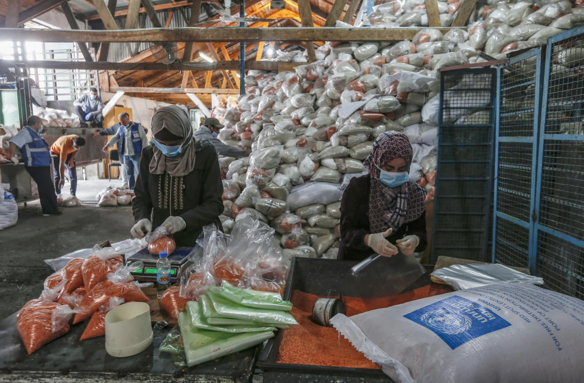 Palestinian employees at the United Nations Relief and Works Agency for Palestinian Refugees (UNRWA) prepare food aid rations. (File/Mahmud Hams/AFP)