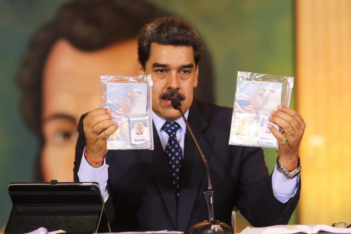Nicolas Maduro holds up the passports of two US citizens arrested by security forces, during a video conference with international media, at Miraflores Presidential Palace in Caracas, on May 6, 2020. (AFP)