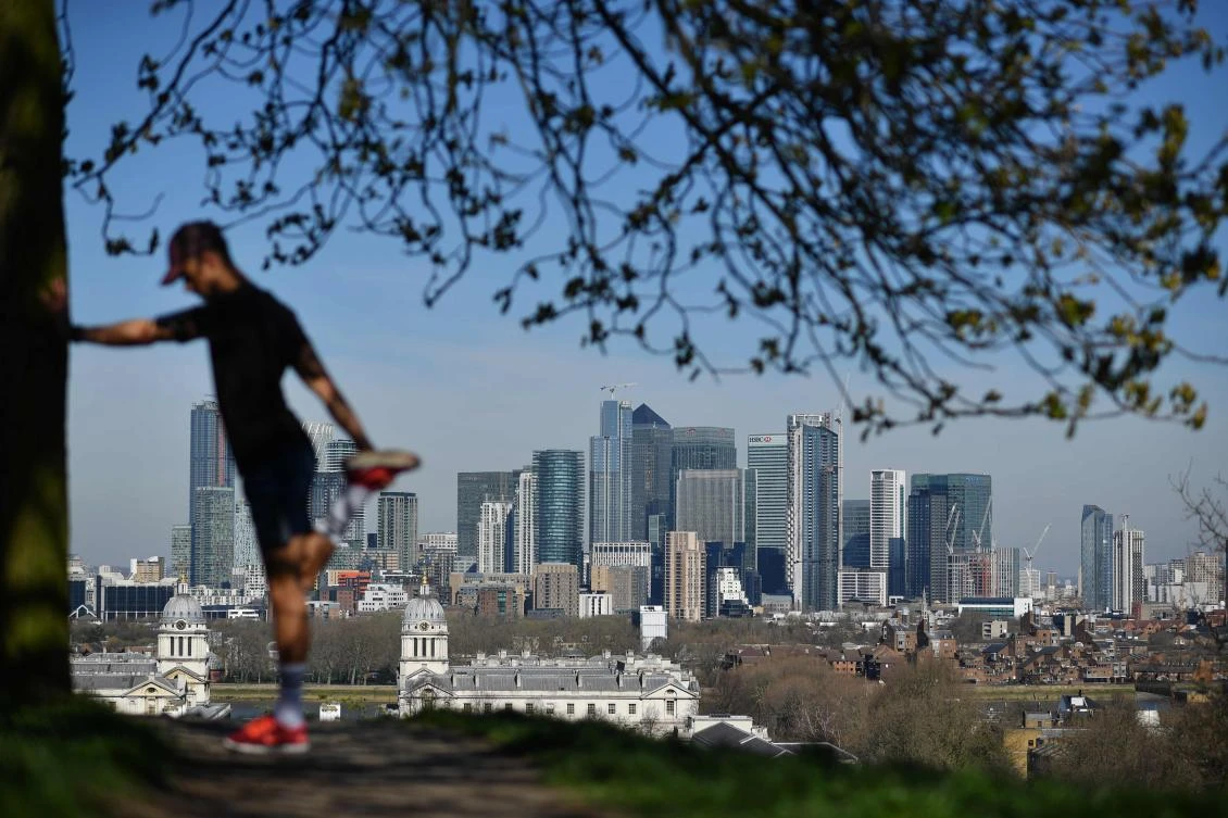 In this file photo taken on March 23, 2020 London's financial district Canary Wharf is seen as a man exercises in Greenwich Park in South London on March 23, 2020, as people come to terms with the governments request for social distancing as the Covid-19 pandemic grips the UK. (AFP)
