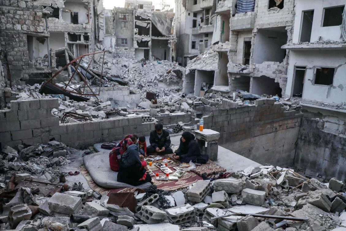 This picture taken on May 4, 2020 during the Muslim holy fasting month of Ramadan shows members of the displaced Syrian family of Tariq Abu Ziad, from the town of Ariha in the southern countryside of the Idlib province, breaking their fast together for the sunset "iftar" meal, in the midst of the rubble of their destroyed home upon their return to the town after fleeing during the previous military assault on the town by Syrian government forces and their allies. (AFP)