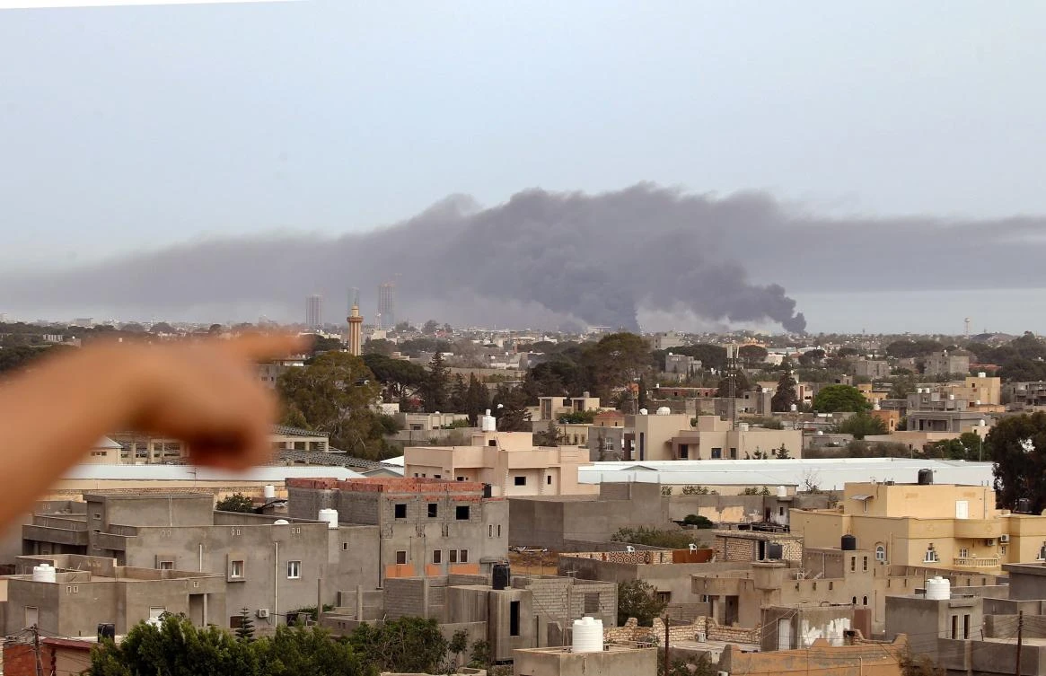 A finger points at smoke rising above buildings in the Libyan capital Tripoli, during reported shelling by strongman Khalifa Haftar’s forces, on May 9, 2020. (AFP)