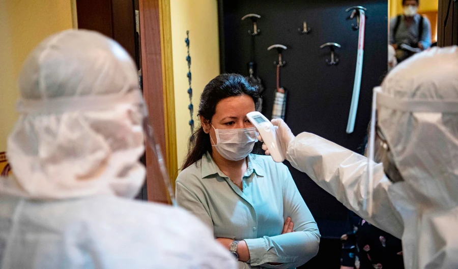 A health officer wearing protective clothing checks the temperature of a resident, believed to have been in contact with coronavirus patients, before collecting swab samples , in Istanbul on May 7, 2020. (AFP)