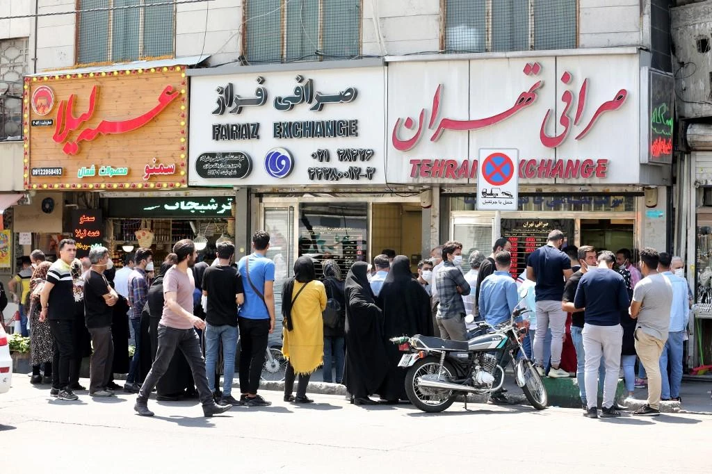 Above, customers ignore anti-contagion protocols as they queue outside a foreign currency dealer in the Sadeghieh district of western Tehran. (AFP)
