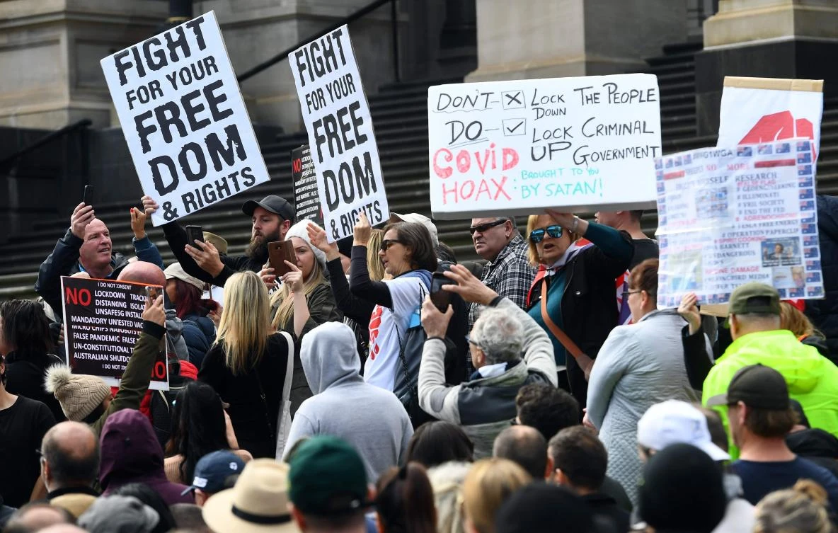 Anti-lockdown protesters hold placards on the steps of Victoria’s state parliament in Melbourne on May 10, 2020. (AFP)