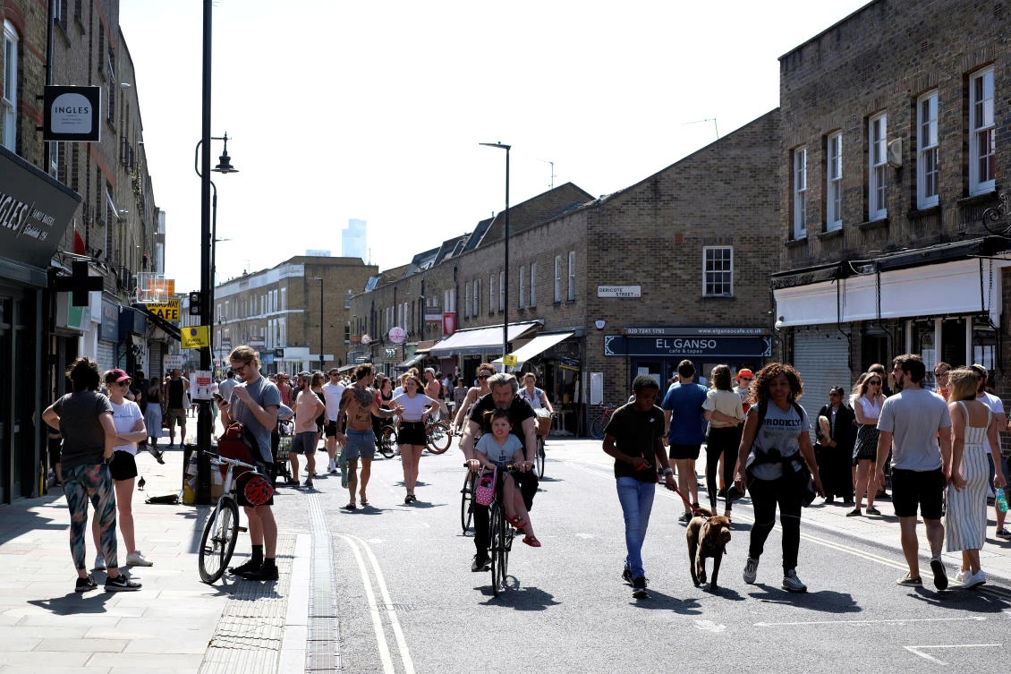People walk and cycle along Broadway Market in London on May 9, 2020 amid an earlier government plea for residents to stay at home to help prevent the spread of coronavirus. (Reuters)