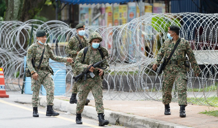 Soldiers wearing face masks patrol next to barbed wire at a newly locked down coronavirus affected area at old town of Petaling Jaya, Malaysia on Sunday. (AP)