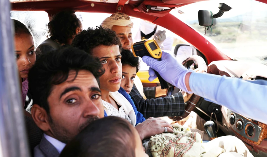 A health worker takes the temperature of people riding a taxi van, amid concerns of the spread of the coronavirus disease, at the main entrance to Sanaa. (Reuters)