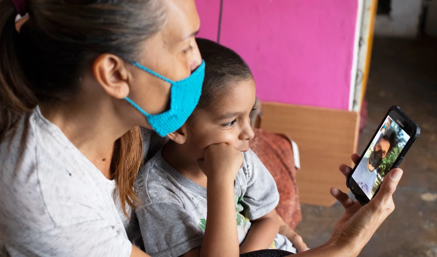 In this April 27, 2020 photo, Daniel sits in grandmother's lap in their apartment in Caracas, Venezuela, as they chat via a messenger service with his father Misael Cocho. (AP)