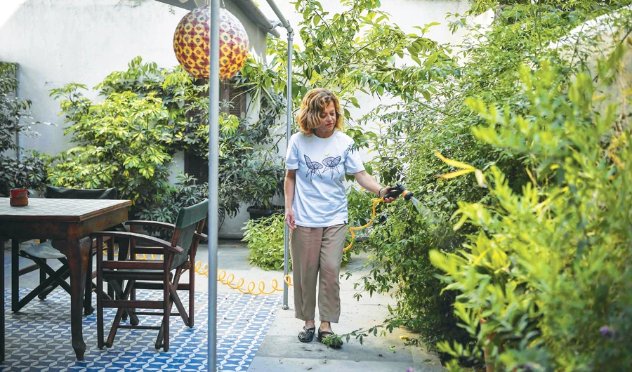Romina Tsitou, owner of two homes in Greece’s Koukaki district available on Airbnb, waters plants at one of them during a lockdown in Athens. (AFP)