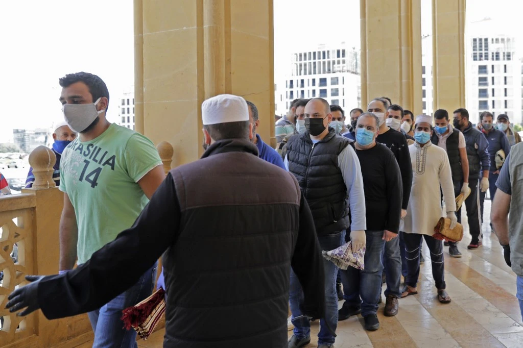 Worshippers wearing protective face masks queue to enter the Mohammed Al-Amin Mosque in the Lebanese capital Beirut's downtown district, to perform the Friday prayers during the Muslim holy month of Ramadan, after some measures that were taken by the authorities in a bid to prevent the spread of the novel coronavirus were eased, on May 8, 2020. (AFP)