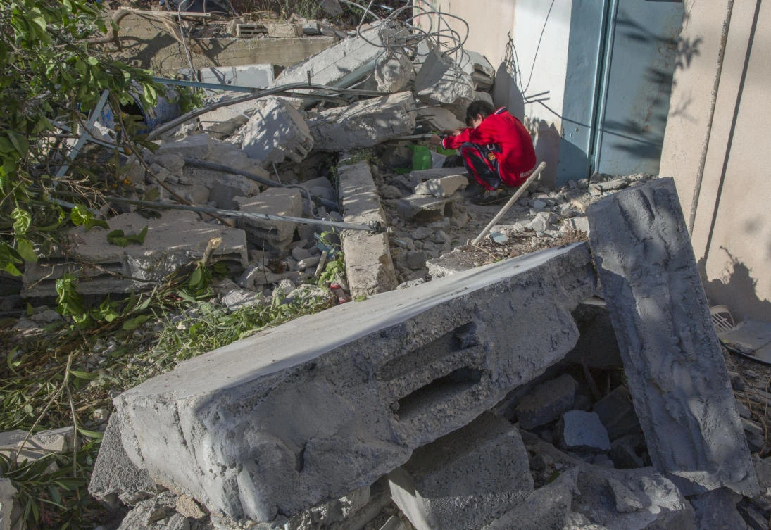 A Palestinian boy tries to salvage an Item from the rubble of the building that was partly demolished by the Israeli army, in the West Bank village of Kobar, near Ramallah, Monday, May 11, 2020. (AP)