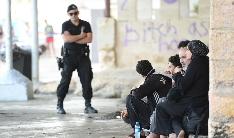 A police officer stands next to a group of nine people, believed to be asylum seekers, who arrived on a speedboat in Marsascala, Malta, on July 1, 2018. (AFP)