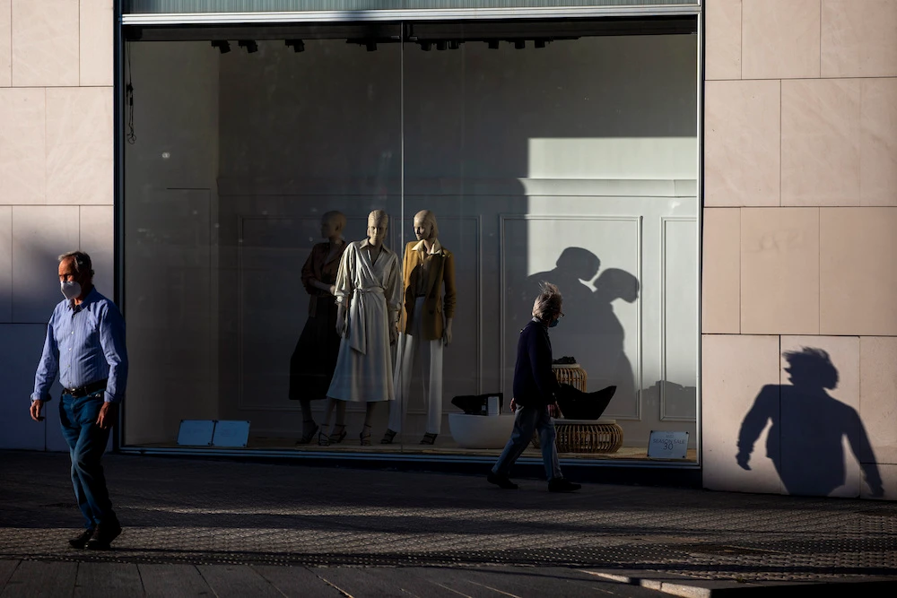 People walk past a closed clothing store in Barcelona, Spain, May 13, 2020. (AP)