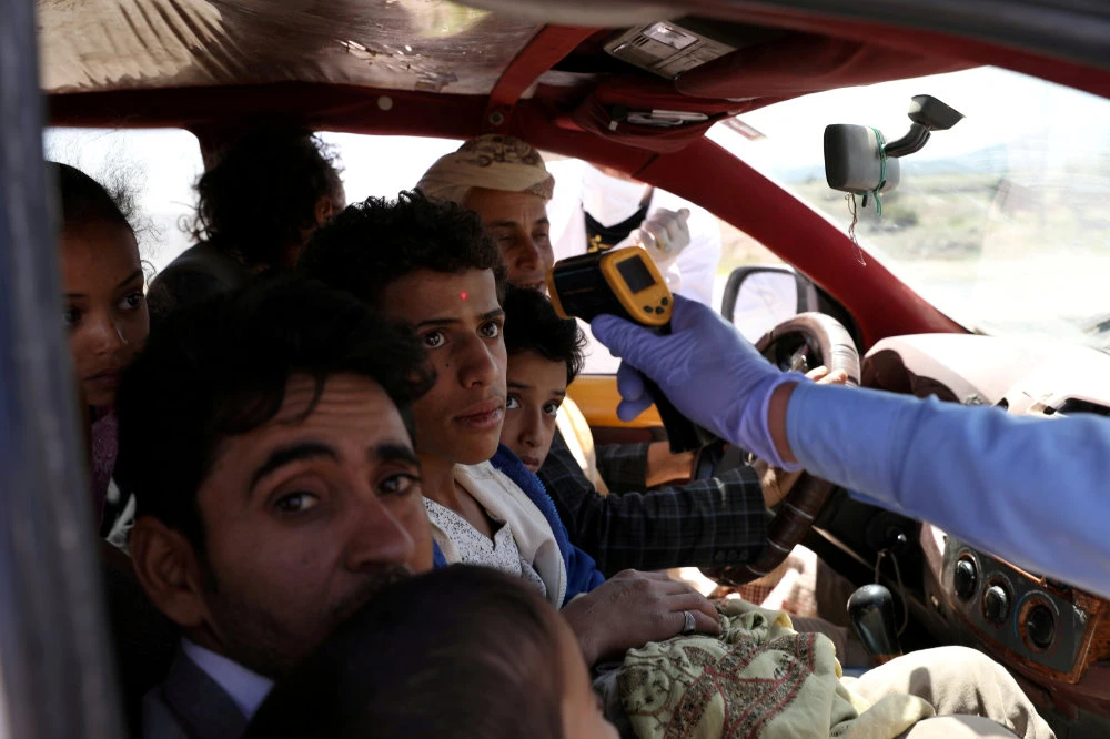 A health worker takes the temperature of people riding a taxi van at the main entrance of Sanaa, Yemen, on May 9, 2020, amid concerns of the spread of COVID-19. (REUTERS File Photo)