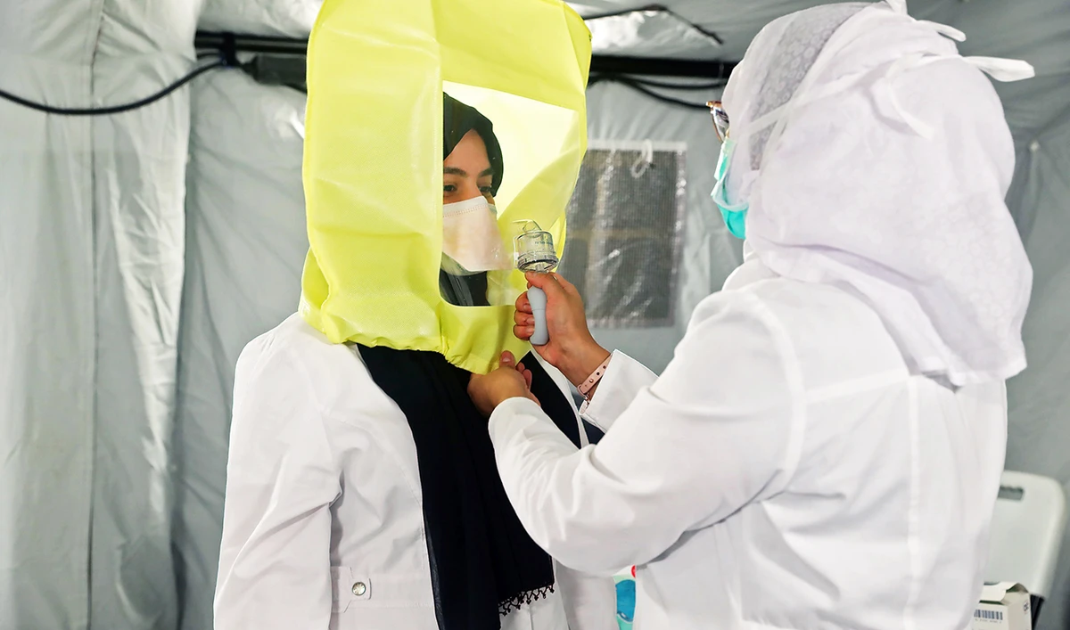 A medical worker assists another to dress up in protective gear at a tent in a newly opened field hospital to treat coronavirus patients in Makkah. (File/AFP)