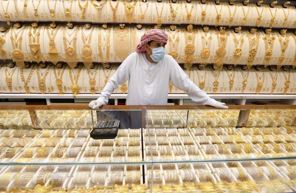 Above, a merchant wears a face mask and gloves at a jewelry shop in Dubai on May 12, 2020 as markets were reopened amidst an easing of pandemic restrictions. (AFP)