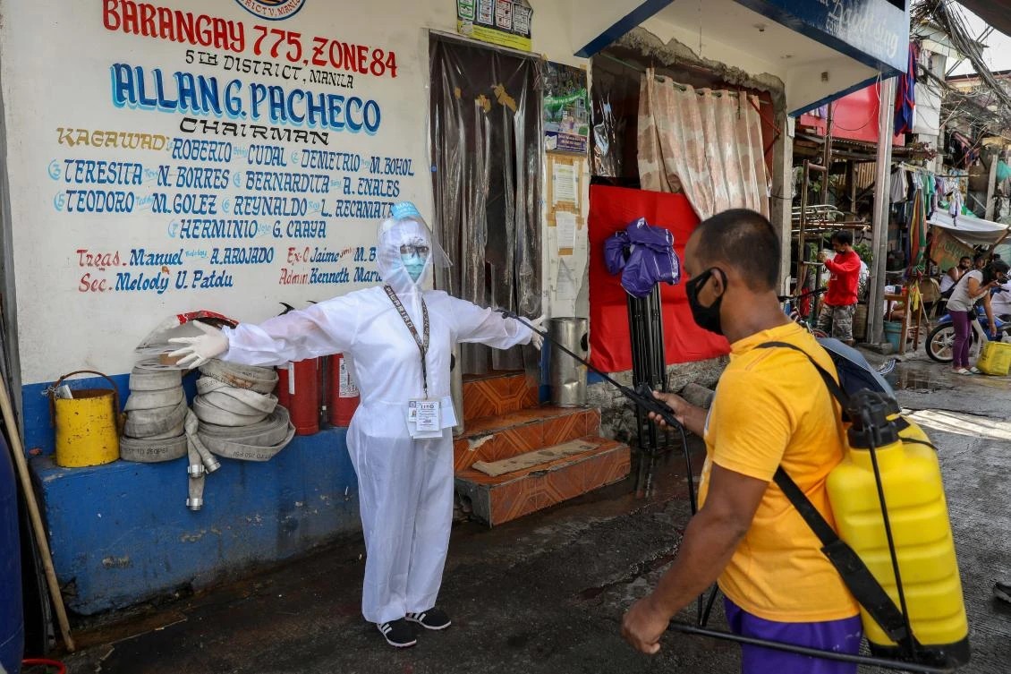 A health care worker in protective suit is disinfected after visiting a house of a suspected COVID-19 case in Manila, Philippines on May 16, 2020. (EPA)