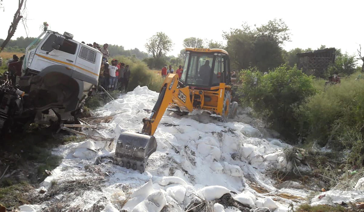An excavator clears bags of white cement scattered on a road after a truck accident near Auraiya, a village in Uttar Pradesh state of India Saturday, May 16, 2020. (AP)