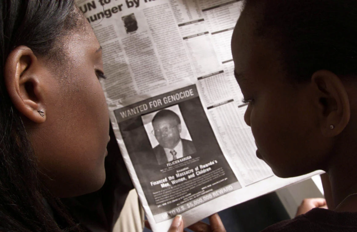 Readers look at a newspaper June 12, 2002 in Nairobi carrying a ‘wanted’ photograph of Rwandan Felicien Kabuga. (Reuters)