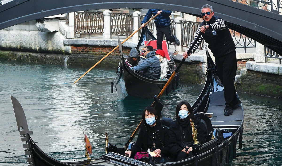 Tourists wearing face masks take a ride on a gondola in Venice before the pandemic shut down tourism in the city. (AFP)