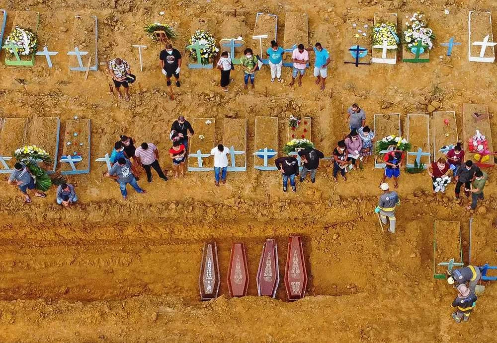 This file aerial picture taken on April 22, 2020 shows a burial taking place at an area where new graves have been dug up at the Nossa Senhora Aparecida cemetery in Manaus, in the Amazon forest in Brazil, during the COVID-19 coronavirus pandemic. AFP / Michael Dantas)