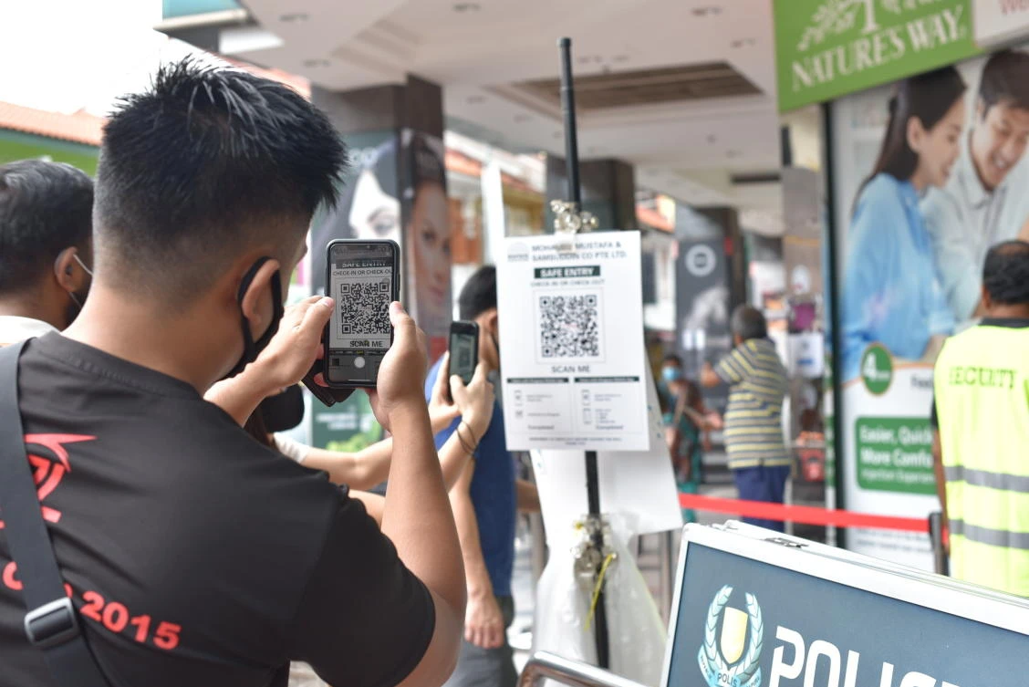 A resident scans a QR code of a digital check-in system that logs every entry to facilitate contact tracing outside the Mustafa Center in Singapore’s Little India district on May 16, 2020. (AP)