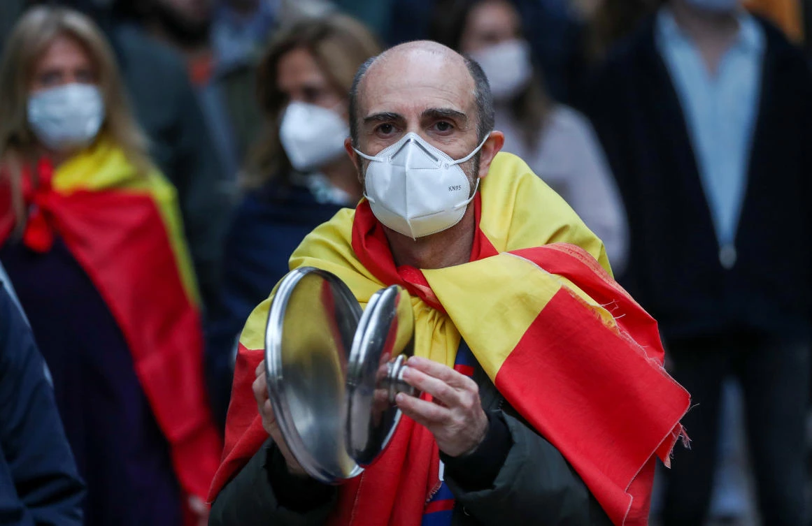 A man wearing a protective face mask and a Spanish flag marches and bangs saucepan lids as he attends a protest against the Spanish government’s handling of the coronavirus crisis in Madrid, Spain on May 16, 2020. (Reuters)
