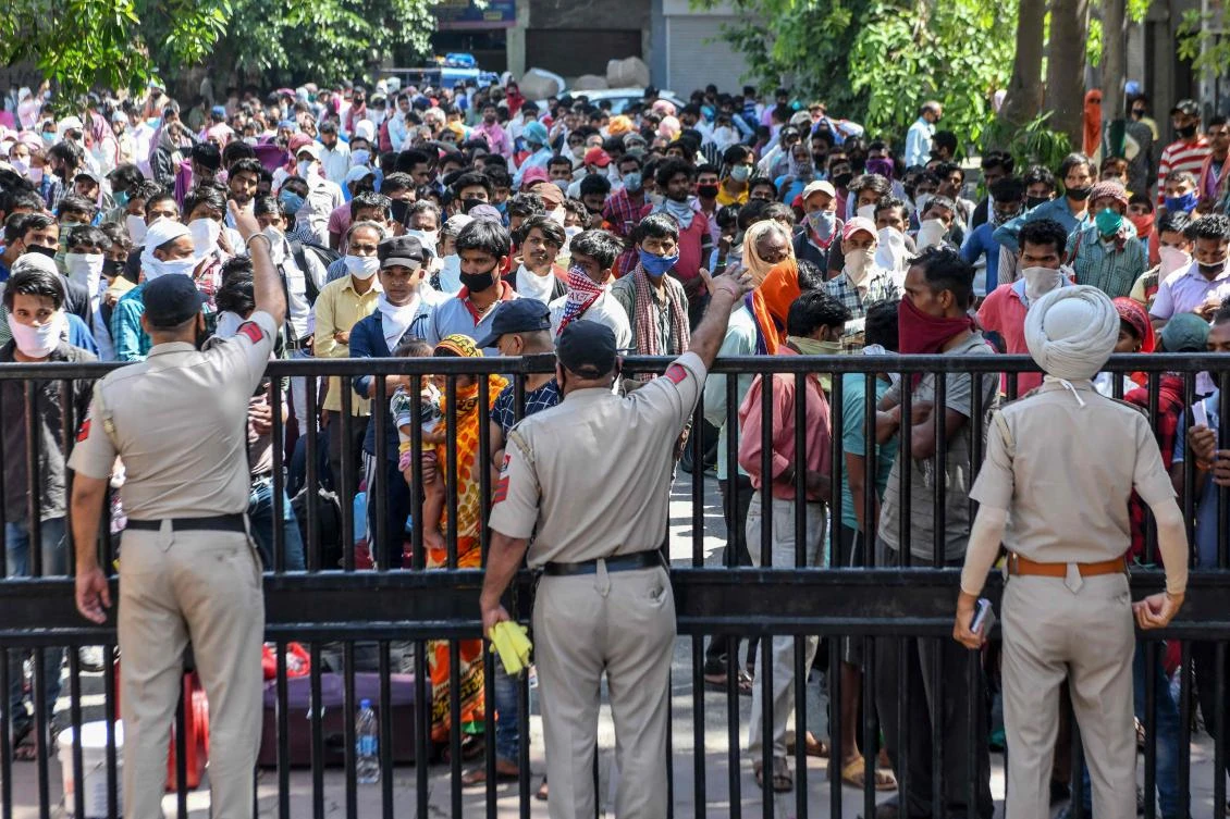 Police personnel stand guard as stranded migrant workers wait to get thermally screened in Amritsar before traveling to their hometowns after the government eased a lockdown on May 17, 2020. (AFP)