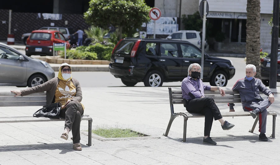 Lebanese wearing face masks sit at Beirut's seaside corniche on May, 13, 2020. (AFP)
