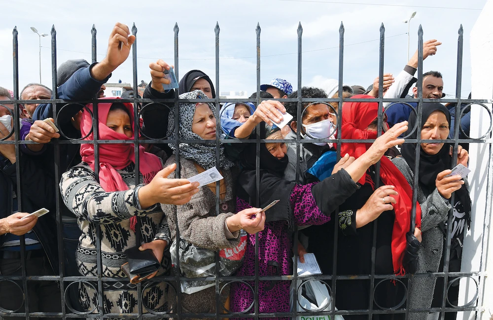 Impoverished Tunisian citizens gather outside Tunis on March 30 to claim the financial aid promised by the government. (AFP)
